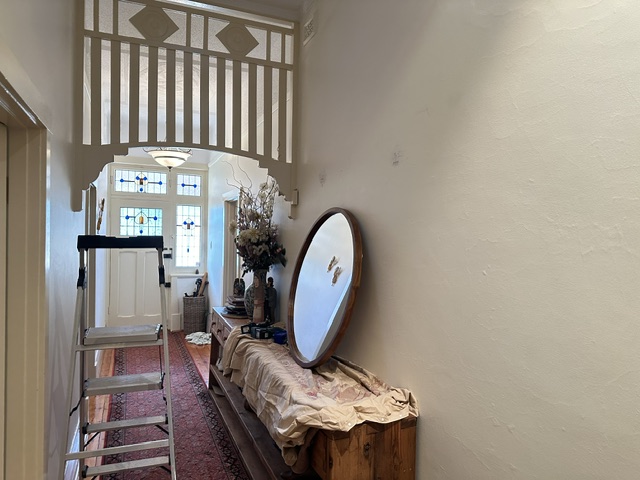 Heavy round mirror waiting on the hall table, ladder set up by the old wall